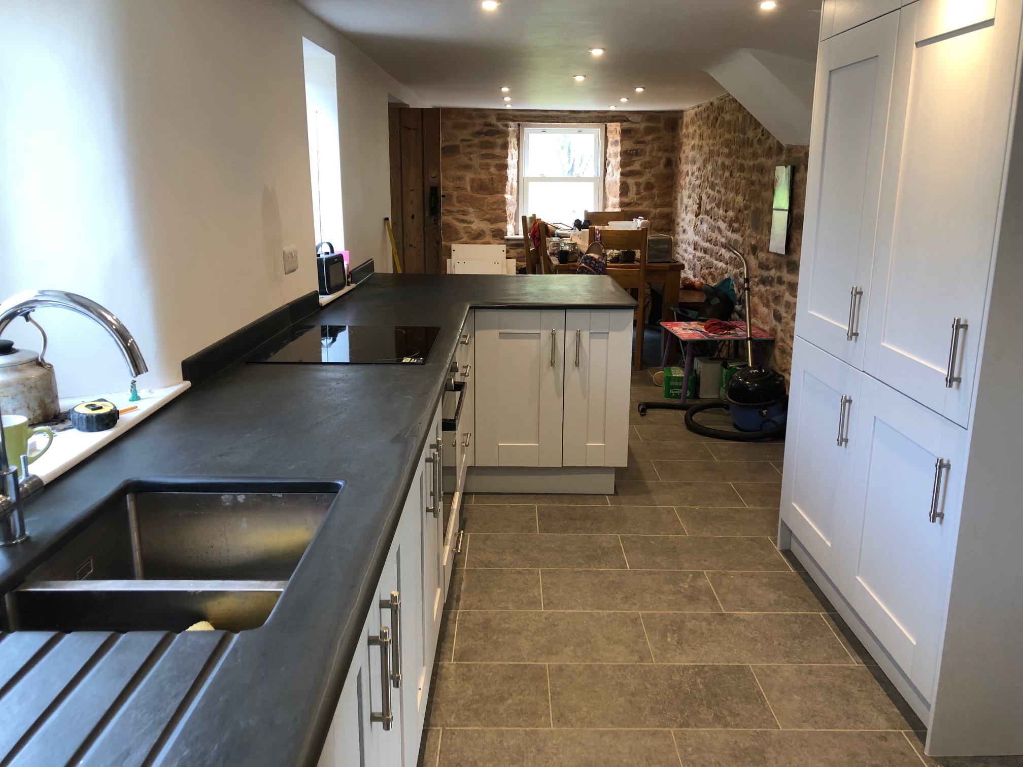 polished slate worktop in a modern cottage kitchen with an exposed stone wall